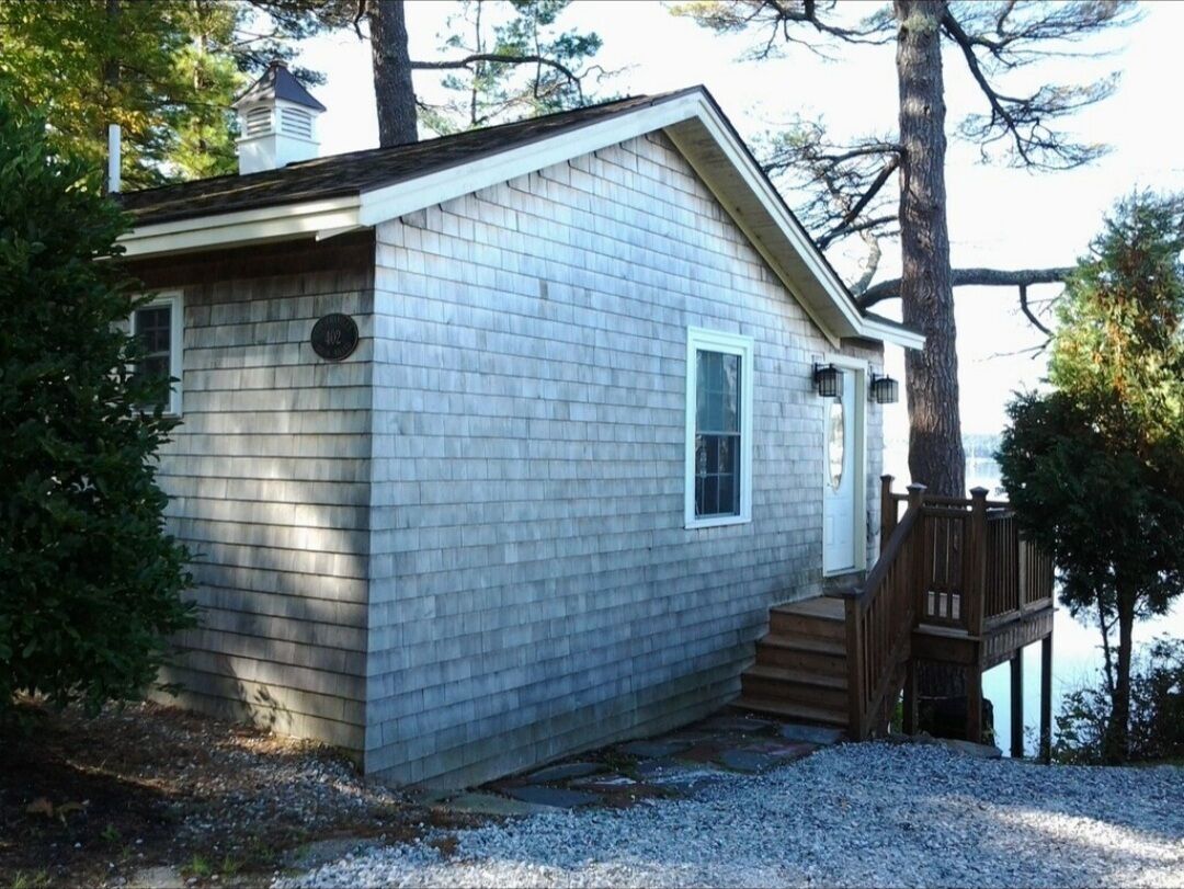 A small, single-story house with a sloped roof, a front door, and a small window.