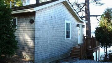 A small, single-story house with a sloped roof, a front door, and a small window.
