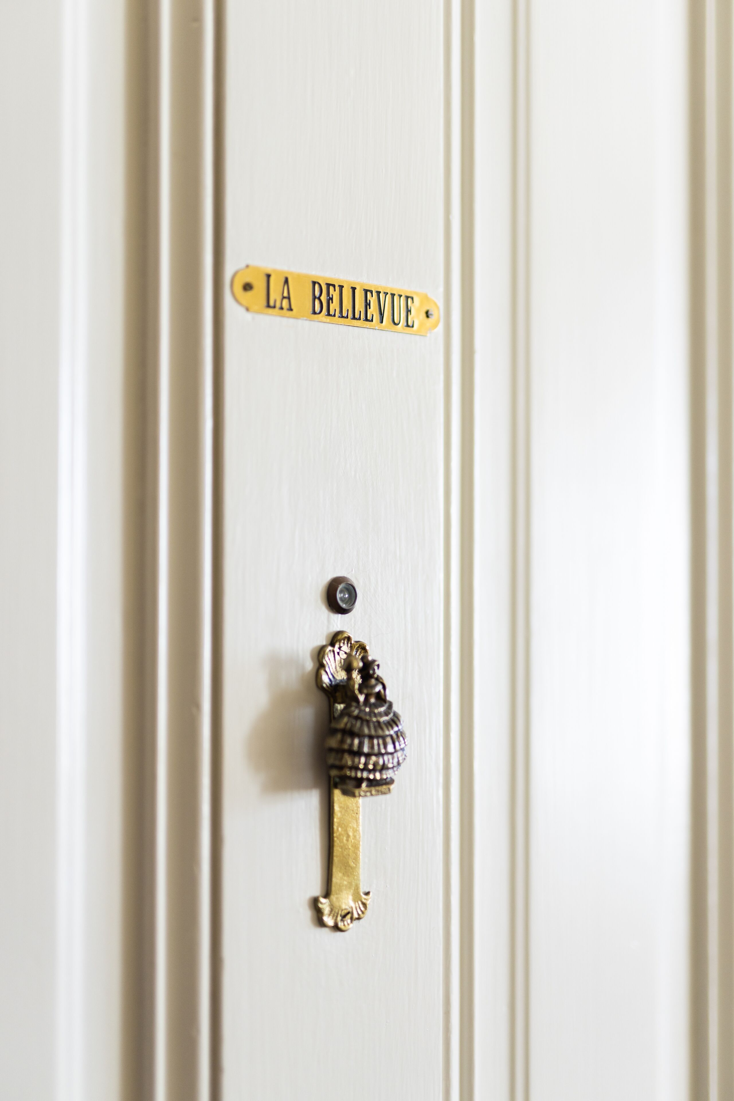 A door with a brass keyhole and a sign that reads "LA BELLEVUE".