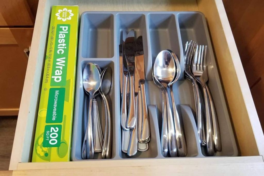 A drawer with compartments containing various kitchen utensils, including spoons, forks, and knives.