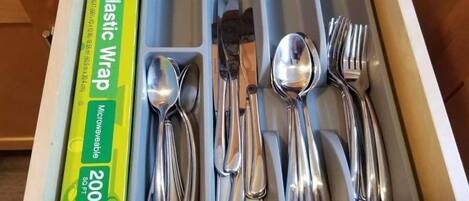 A drawer with compartments containing various kitchen utensils, including spoons, forks, and knives.