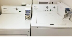 Deux machines à laver Whirlpool dotées de panneaux de commande, une étiquette indiquant le prix et un mur blanc en arrière-plan.
