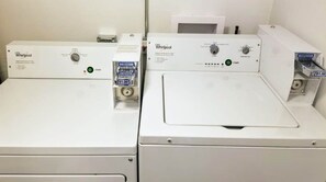 Dos lavadoras Whirlpool con paneles de control, una etiqueta de precio y una pared blanca al fondo.