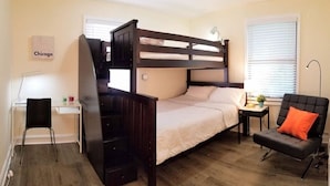Une chambre avec un lit superposé, un bureau, une chaise et une petite table avec une lampe.