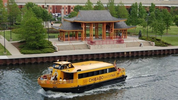 Un bateau jaune avec l’inscription « CHICAGO WATERTAXI » sur le côté, naviguant sur l’eau.