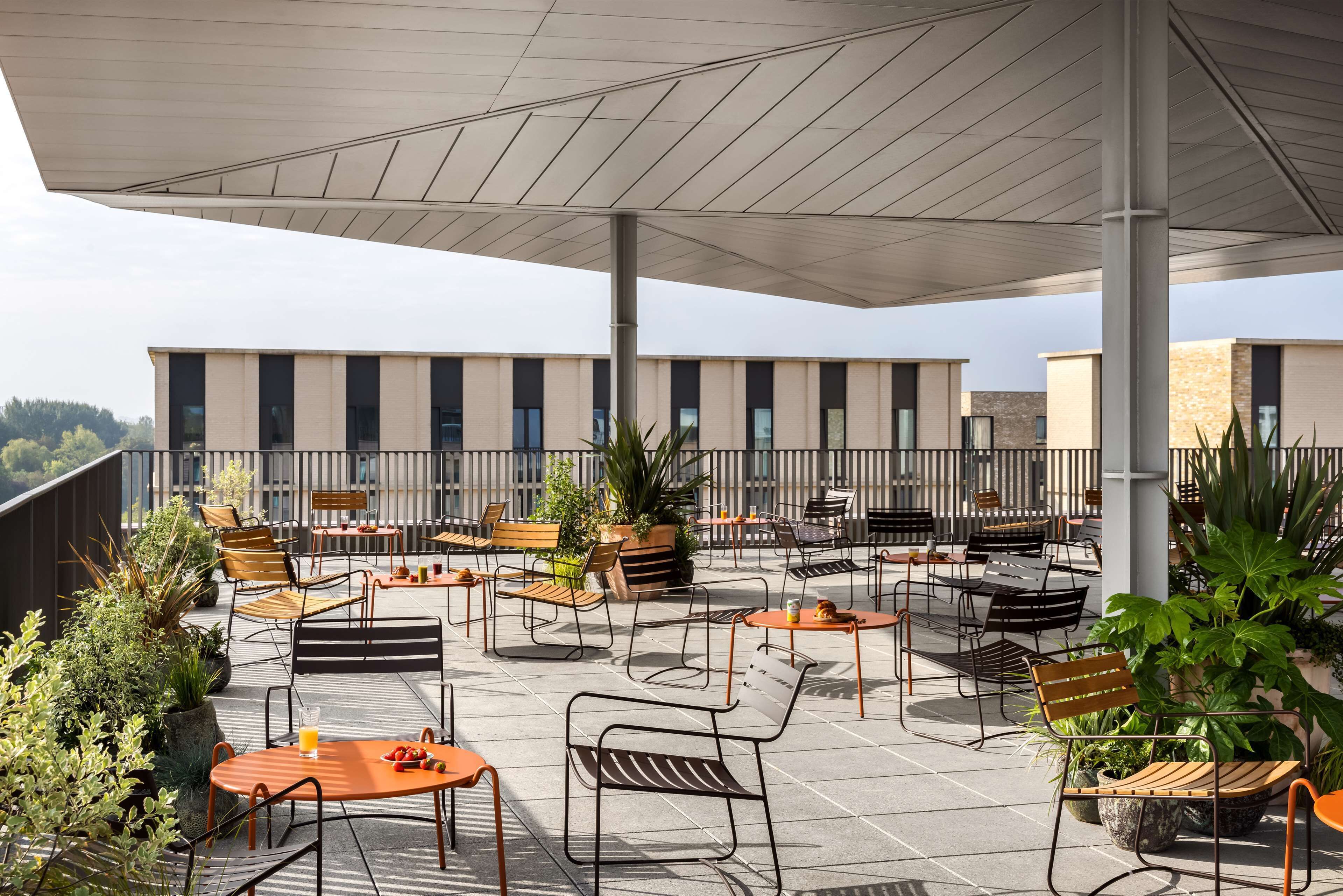 A rooftop terrace with outdoor seating, potted plants, and a view of the building's exterior.