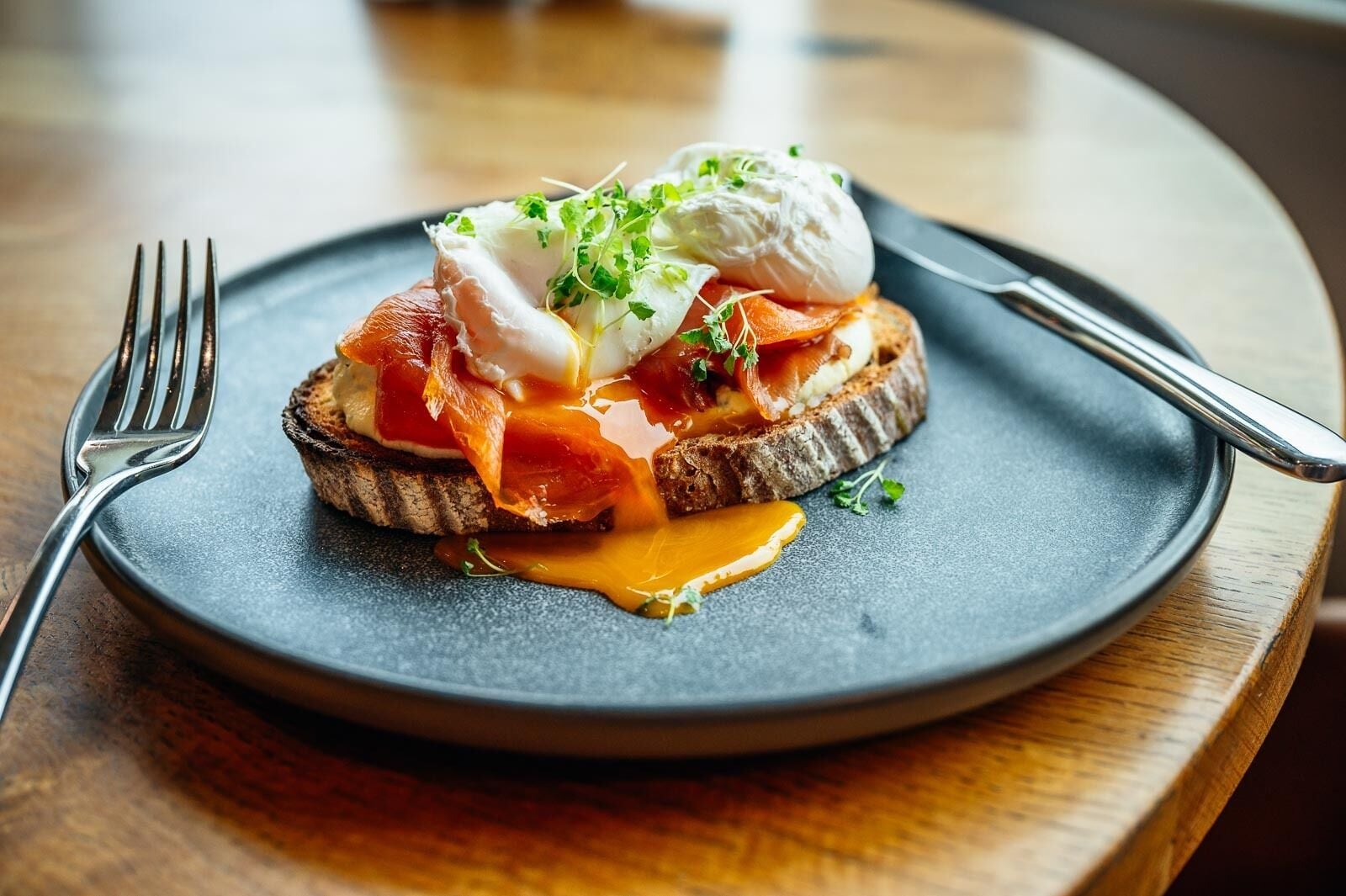 A breakfast dish on a plate with a fork and knife beside it.
