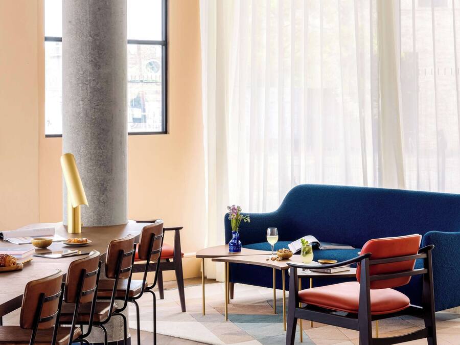 A modern dining area with a large table, chairs, and a blue sofa.