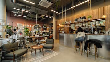 Un espace bar moderne, doté de sièges, d’étagères remplies de bouteilles et d’un comptoir.