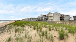 A beachfront property with multiple buildings, a sandy beach, and grassy dunes.