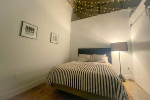 A bedroom with a bed, a floor lamp, and string lights. - The coolest loft in Cincinnati Area (Maineville)