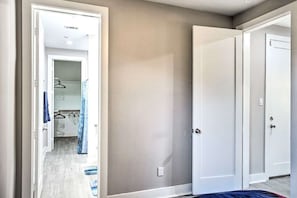 A bedroom with a walk-in closet, a door with a handle, and a light switch on the wall.