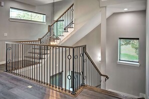 A modern staircase with a metal railing and wooden steps, leading to an upper floor. - NEW! Beautiful 3 story Houston Home (Houston)