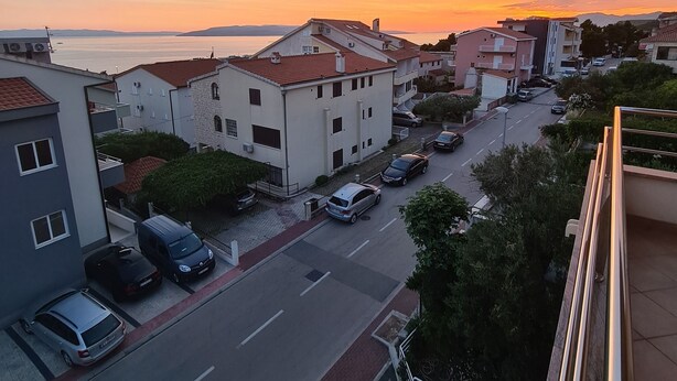 Eine Wohnstraße mit Häusern und parkenden Autos im Abendlicht.
