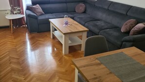 Ein modernes Wohnzimmer mit einer Couch, einem Holztisch und einem kleinen Beistelltisch.