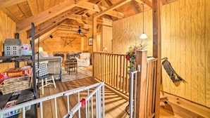 Interior acolhedor de uma cabana de madeira com um quarto no mezanino, uma sala de jantar e uma sala de estar.