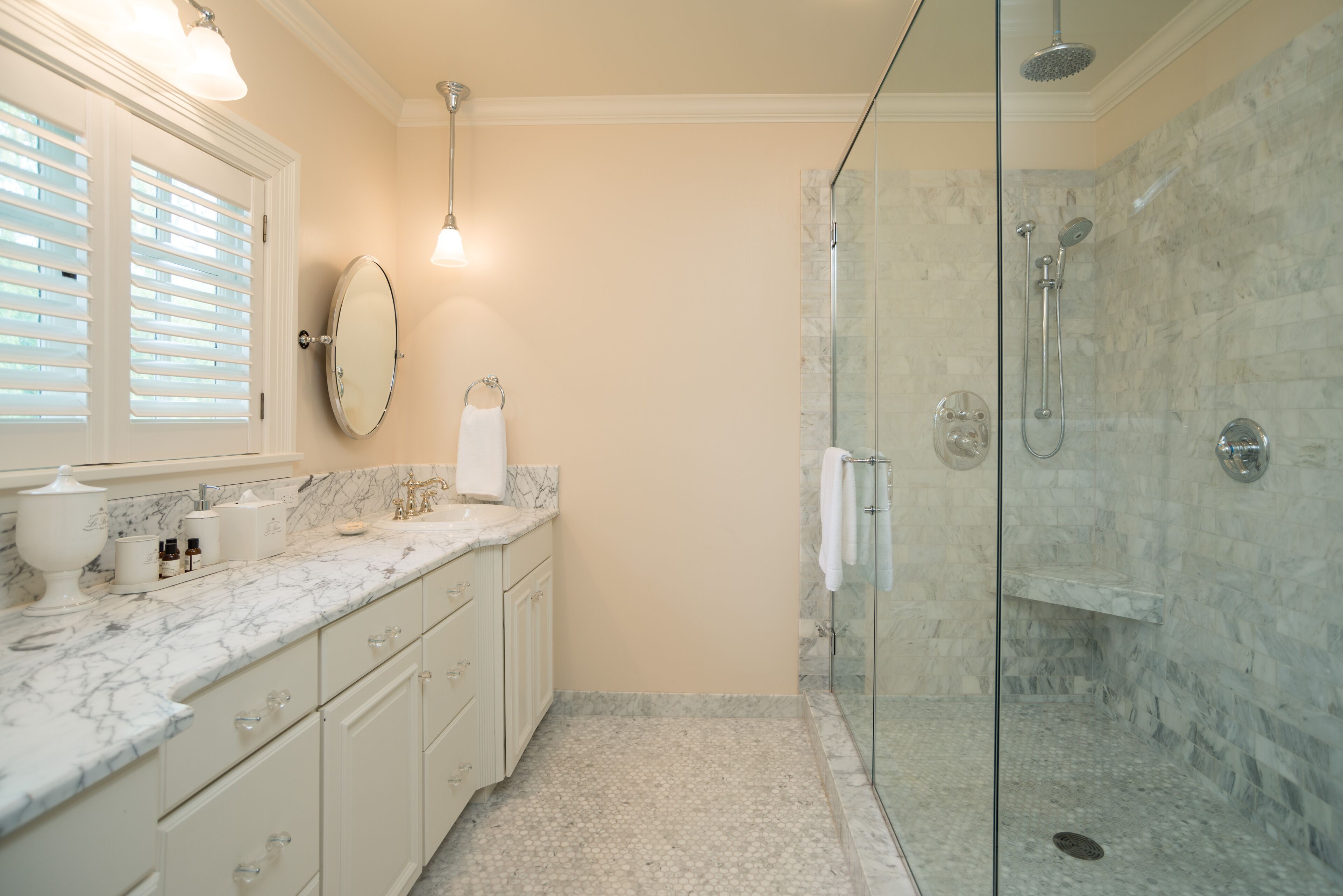A bathroom with a marble countertop, a glass shower enclosure, and a white sink.
