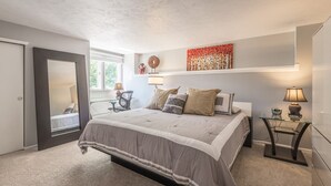A bedroom with a large bed, bedside tables, a desk, and a chair. - Fully stocked new apt, work from home + Free Parking! (Denver)