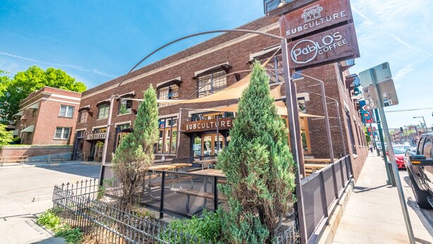 A brick building with a sign for 'Subculture' and 'Pablo's Coffee' on the ground floor. - Fully stocked new apt, work from home + Free Parking! (Denver)