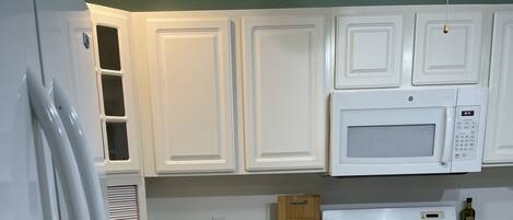 A kitchen with white cabinets, a microwave, a stove, and a sink.