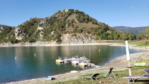 A lakeside view with boats docked, a chair, and a table on the shore. - Amazing Lake View (Castel di Tora)