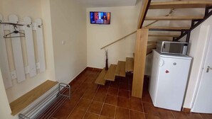 A staircase with wooden railings leading to a landing. A small white refrigerator and a microwave are placed on the landing. - Holiday home with pool and garden shower (Badacsony)