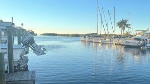 A marina with several boats docked, a boat lift, and a clear sky. - Waterfront Home in Gulf Harbors with Deepwater Access to Gulf with No Bridges (New Port Richey)
