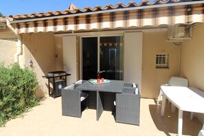 Enjoy al fresco dining and cooking at this outdoor patio, featuring a large table, grill, and comfortable seating.
