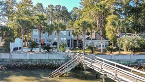 A waterfront property with a wooden bridge, multiple buildings, and palm trees. - Dreamworthy, waterfront St. Helena home with pool and deep water dock. (St. Helena)