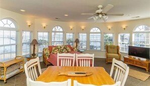 Relax in this spacious room with a dining table, sofa, and television, offering a comfortable seating area and a balcony view.