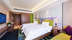 Habitación de hotel con dos camas, un televisor, un escritorio y un mural con vistas a la ciudad.