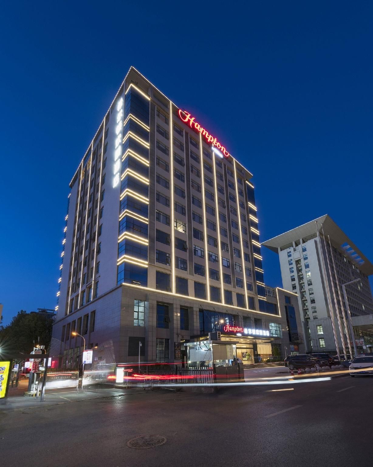 A multi-story hotel with a prominent red sign, a modern facade, and a well-lit entrance.