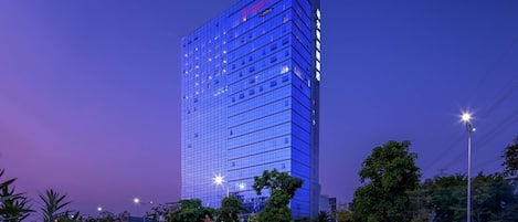 A high-rise hotel with a modern glass facade, multiple floors, and a prominent signage at the top.