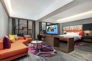 Ein modernes Hotelzimmer mit Sofa, Bett, Schreibtisch und Fernseher.