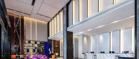 A spacious lobby with a reception desk, seating area, and a large bookshelf.