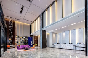 A spacious lobby with a reception desk, seating area, and a large bookshelf.