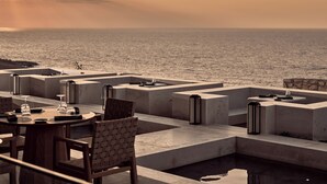 A modern outdoor dining area with a pool, tables, chairs, and a view of the sea at sunset. - The Royal Senses Resort & Spa Crete, Curio Collect (Mylopotamos)