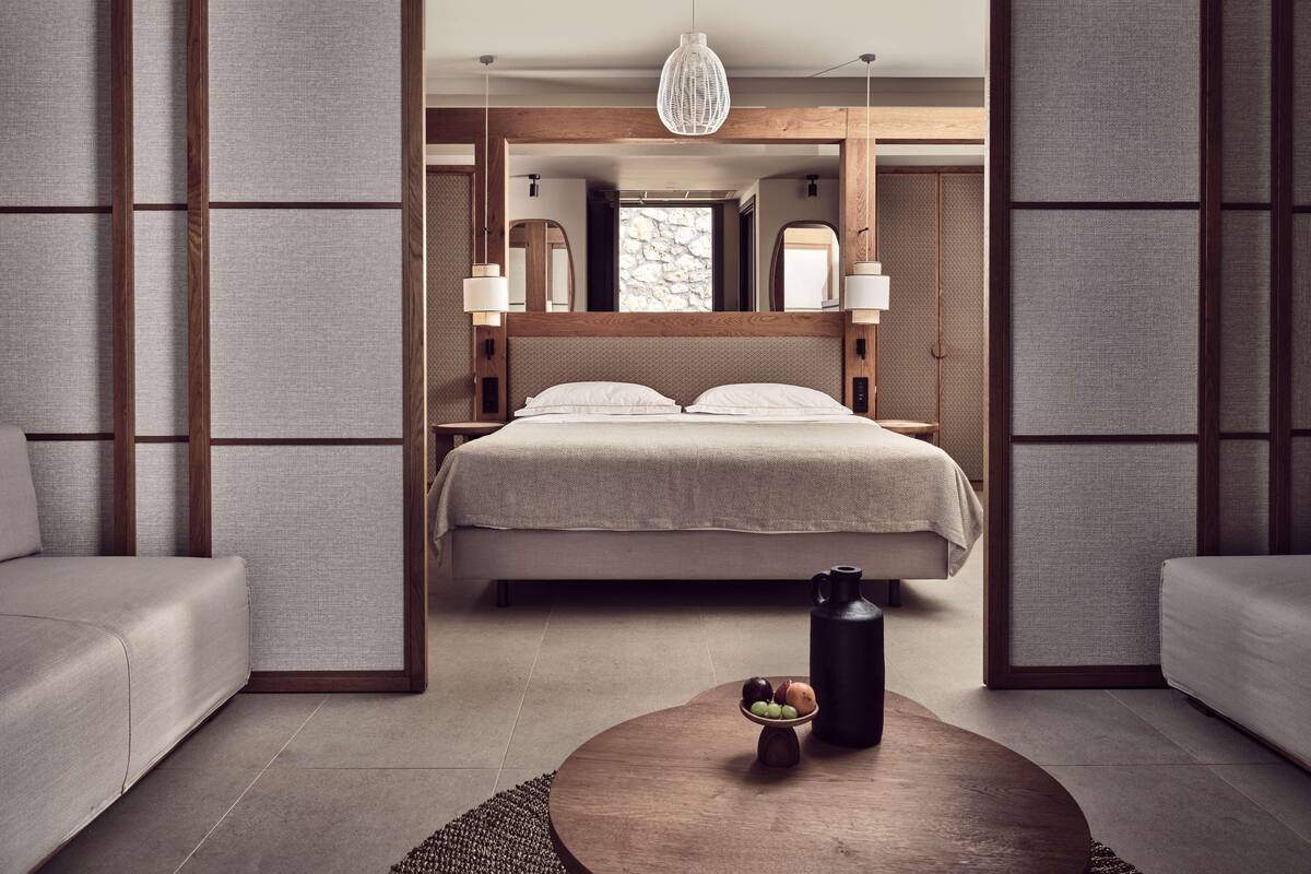 A modern bedroom with a bed, bedside tables, a hanging light fixture, and a coffee table with fruit.