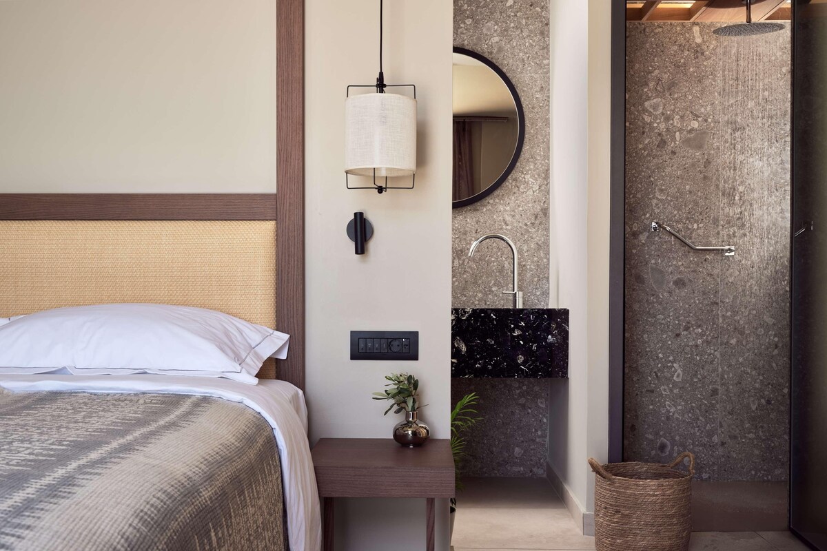 A bedroom with a bed, bedside table, and a wall-mounted light fixture.