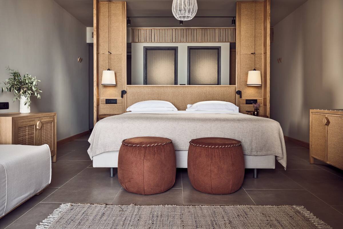 A modern bedroom with a large bed, two side tables, a hanging light fixture, and a woven headboard.