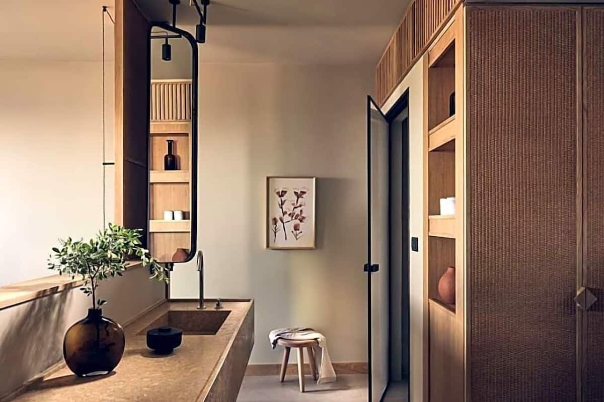 A modern bathroom with a wooden vanity, a large mirror, and a potted plant.