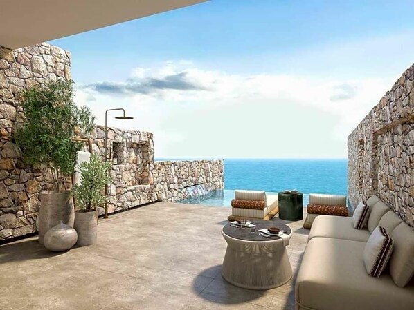 Un espacio exterior amplio con pared de piedra, un sofá y una mesa redonda.