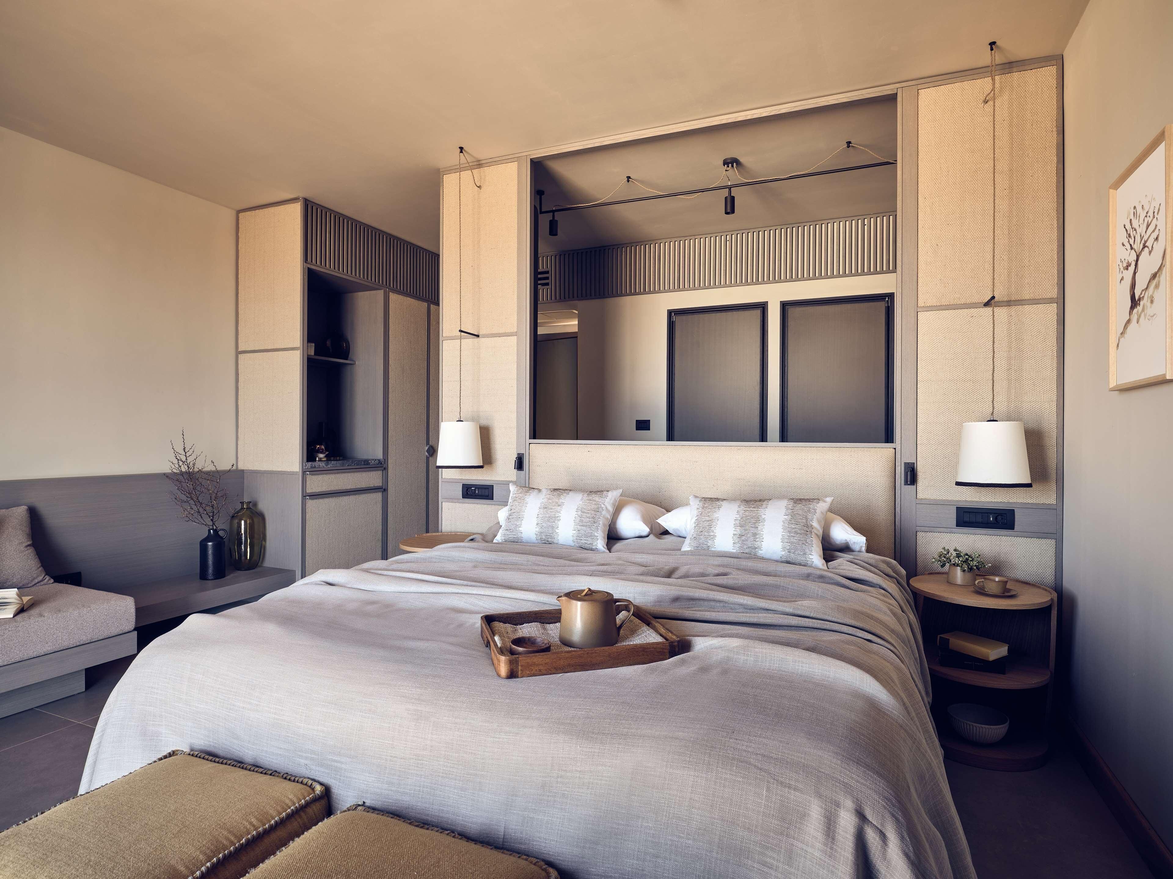 Une chambre d’hôtel moderne dotée d’un grand lit, de tables de chevet, d’un canapé et d’une armoire intégrée.