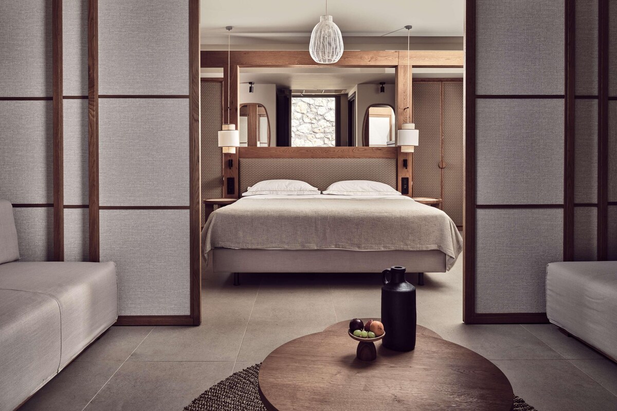A modern bedroom with a bed, bedside tables, a hanging light fixture, and a coffee table with fruit.