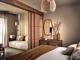A modern bedroom with a large bed, a wooden wardrobe, a mirror, and a hanging light fixture.