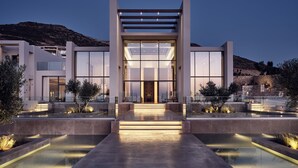 A modern building with a central entrance, glass doors, and a water feature in front. - The Royal Senses Resort & Spa Crete, Curio Collect (Mylopotamos)