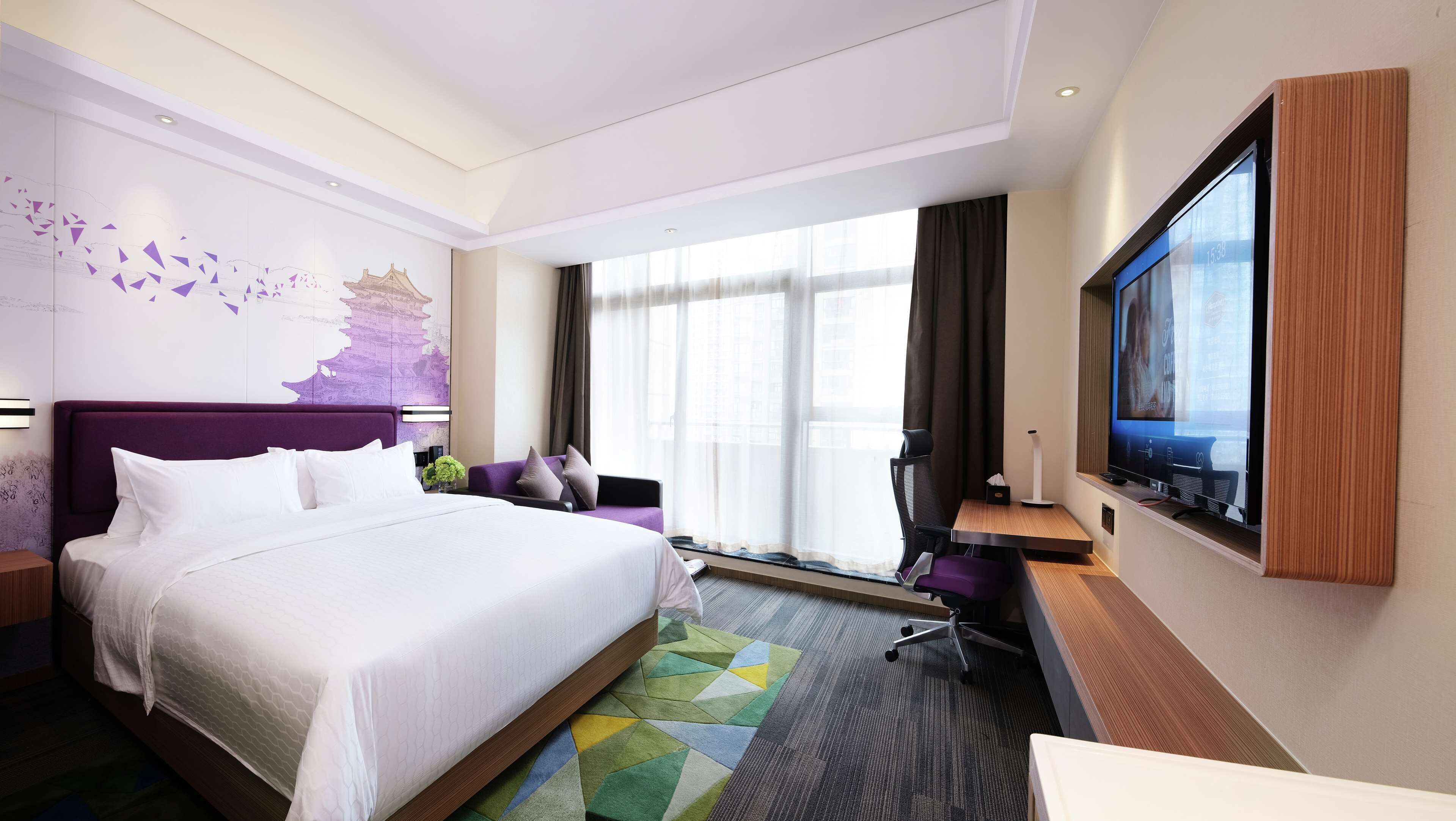 Habitación de hotel con una cama grande, un escritorio con televisor y una ventana con cortinas.