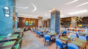 A modern restaurant with multiple dining tables and chairs, a bar area, and a marble wall.
