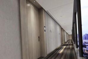 A hotel corridor with a carpeted floor, wooden walls, and a city view through large windows. - Hampton Apartments by Hilton Shenzhen Futian Mangrove Park (Shenzhen)