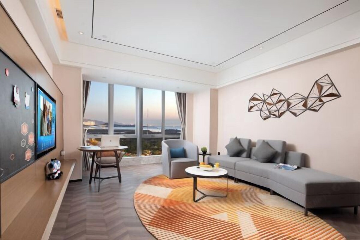 Une chambre d’hôtel moderne dotée d’une grande fenêtre, d’un canapé, d’une table basse et d’un élément décoratif mural.